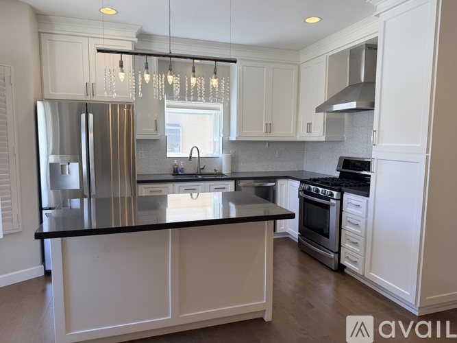 A kitchen with white cabinets and a black countertop.