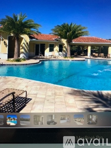 A pool with a house and palm trees in the background.