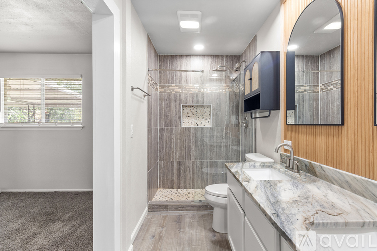 A bathroom with a marble countertop and a walk-in shower.