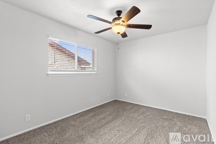 A room with a ceiling fan and a window with blinds.