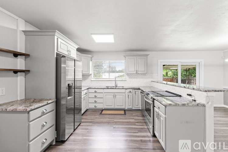 A kitchen with white cabinets and a marble countertop.