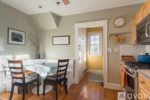 A kitchen with a table and chairs in the foreground and a yellow wall in the background.