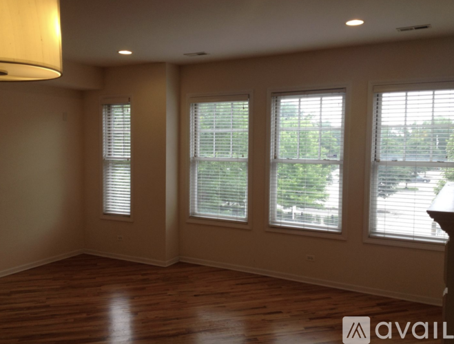A room with wooden floors and three windows.