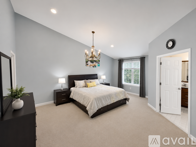 A bedroom with a large bed, a chandelier, and a mirror on the wall.