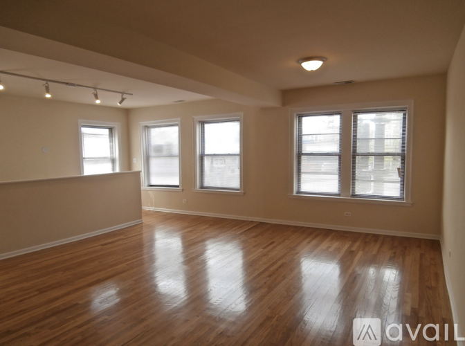Empty room with wooden floors and three windows.