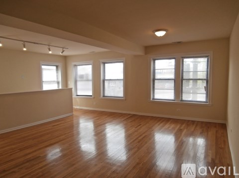 Empty room with wooden floors and three windows.