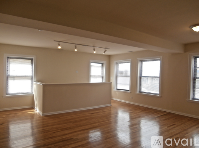 Empty room with wooden floors and three windows.