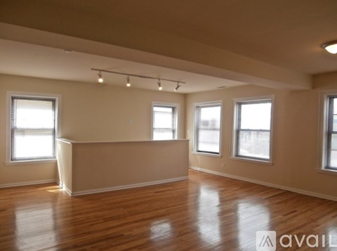 Empty room with wooden floors and three windows.