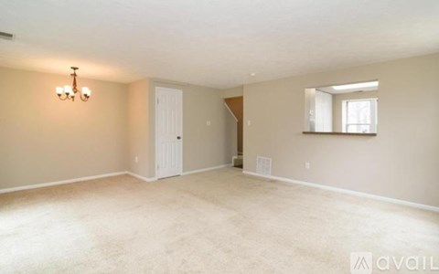 A spacious room with beige carpeting and a chandelier.