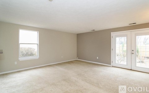 A spacious room with a carpeted floor and a sliding glass door leading outside.