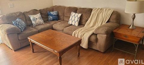 A brown couch with a blanket on it sits in a living room.