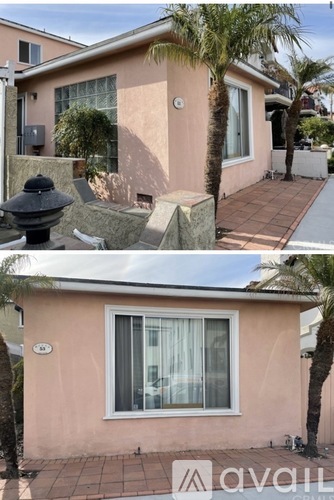 A house with a pink exterior and a palm tree in front.