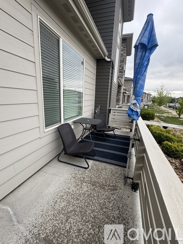 A patio with a chair and an umbrella.