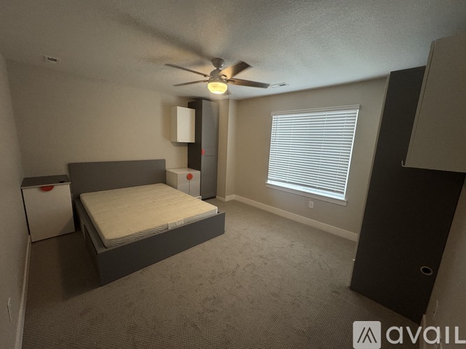 A bedroom with a bed, dresser, and window with blinds.