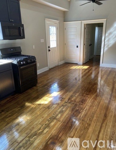 A kitchen with wooden floors and a black stove top oven.