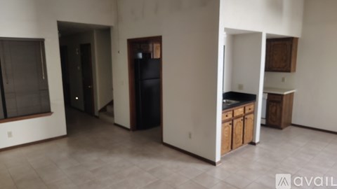 A kitchen area with wooden cabinets and a refrigerator.