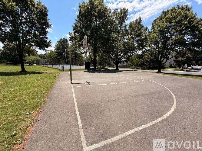 A tennis court surrounded by trees and a fence.