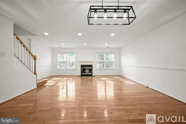 A spacious room with wooden flooring and a fireplace.
