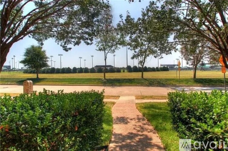 A pathway leads through a grassy area with trees on either side.