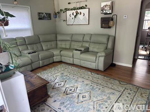 A living room with a green sofa and a rug.