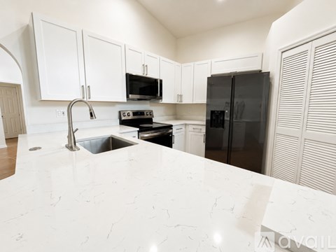A kitchen with white cabinets and a black refrigerator.