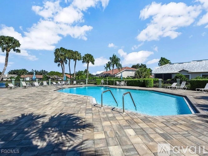 A large swimming pool surrounded by palm trees and lounge chairs.