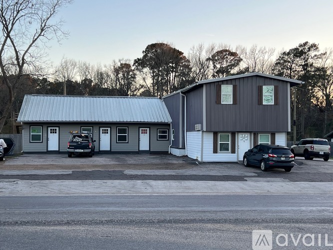 A building with a grey roof and a sign that says "AVAIL" in front of it.