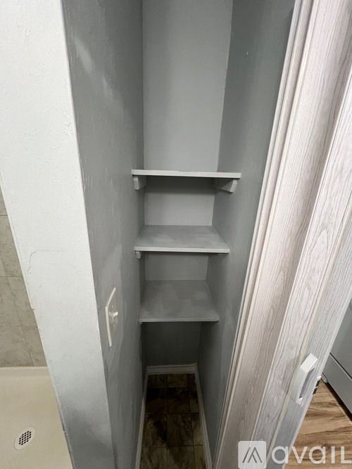 A white shelf in a narrow space under a door.