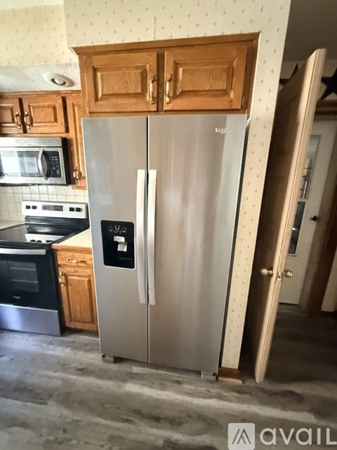 A silver refrigerator in a kitchen with wooden cabinets.