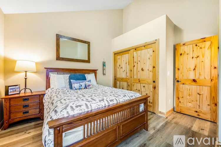 A bedroom with a bed, nightstand, and two wooden doors.