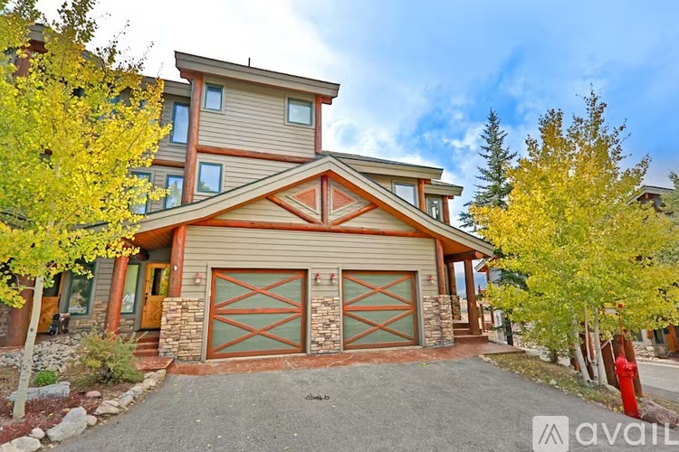 A house with a brown and beige exterior and a red garage door.
