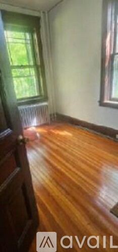 A room with wooden floors and a window with green curtains.