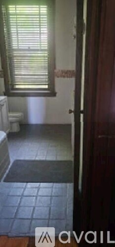 A bathroom with a toilet and a window with blinds.