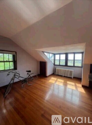 A room with wooden floors and a bicycle is available for rent.
