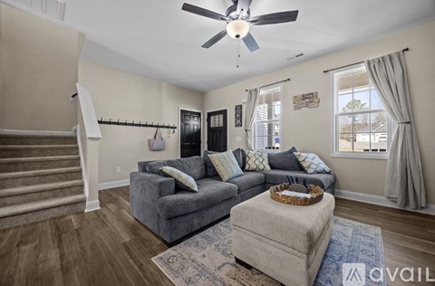 A living room with a grey couch and a fan on the ceiling.