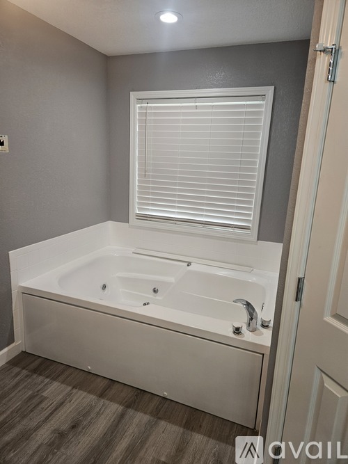 A white bathtub with a window above it in a bathroom.