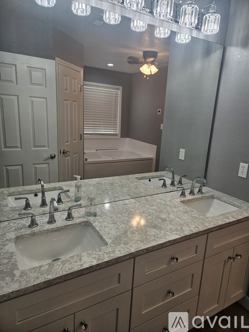 A bathroom with a marble countertop and a chandelier.