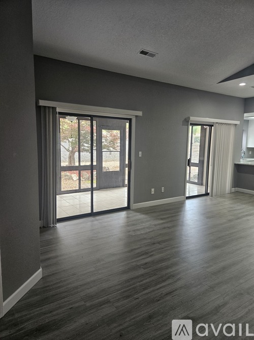 A room with grey walls and wooden flooring, featuring a large sliding glass door.
