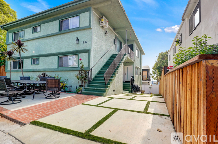 A green and white two story apartment building with a patio and a bicycle.