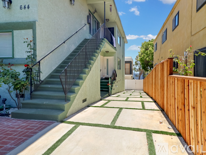 A narrow alley with a staircase and a wooden fence on the right side.