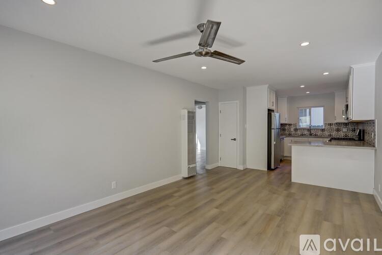 A spacious room with a ceiling fan and wooden flooring.