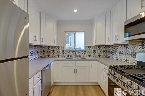 A kitchen with white cabinets and a black and white tiled backsplash.