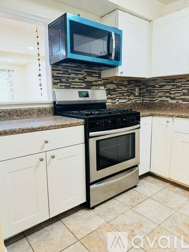 A kitchen with a black stove top oven and a blue microwave above it.