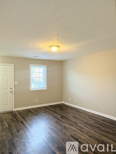 A room with a window and wooden flooring.