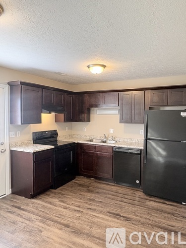 A kitchen with dark wood cabinets and a black refrigerator.
