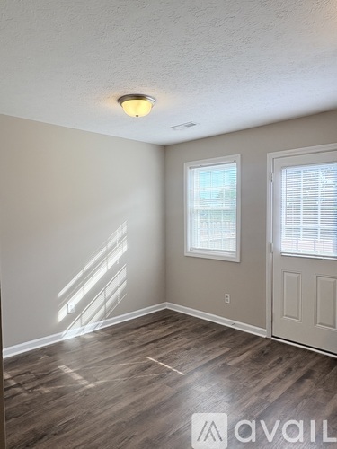 A room with a wooden floor and a window with blinds.