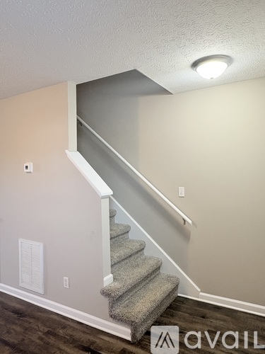 A staircase with a carpeted runner and a white riser.