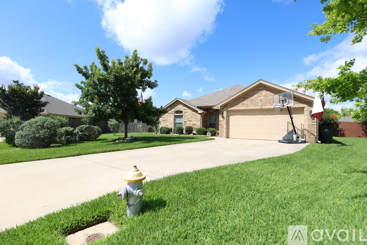 A yellow fire hydrant is on the green grass in front of a house.