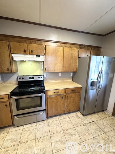 A kitchen with wooden cabinets and a stainless steel refrigerator.