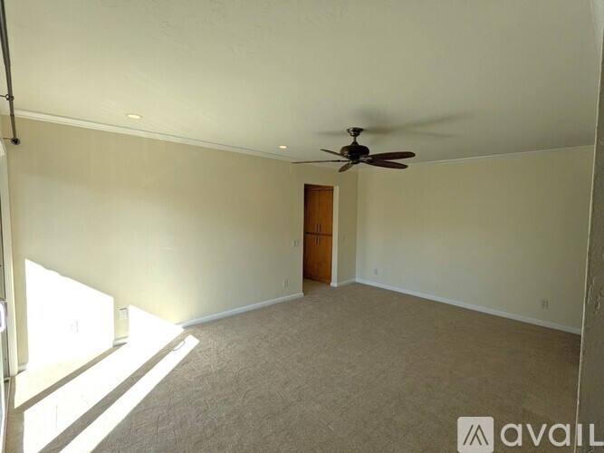 A room with a ceiling fan and a door.